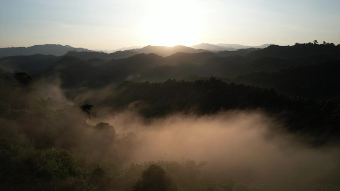在泰国南省美丽的大自然中，太阳从山上升起，晨雾缭绕。