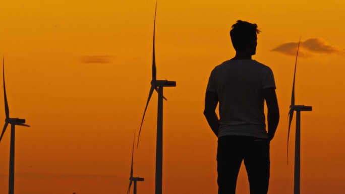 投资未来:土地所有者对风力涡轮机的骄傲注视。清洁能源。拥有风力涡轮机的绿色能源农场。