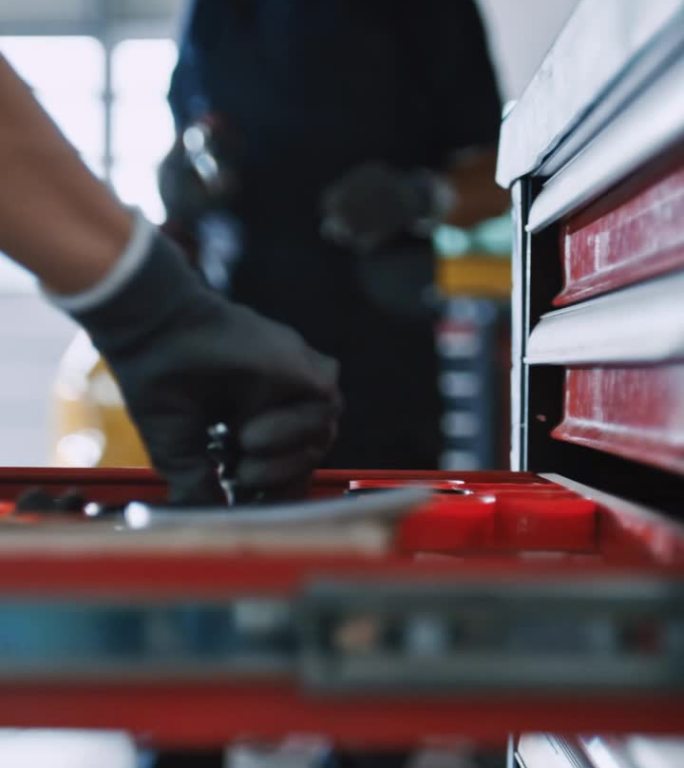 机械师在汽车修理厂的工具箱推车抽屉里寻找工具