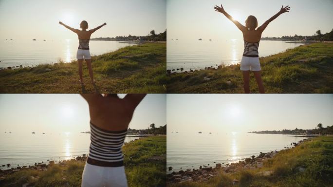 在日落时分，悠闲的女子举起双臂享受湖岸的孤独