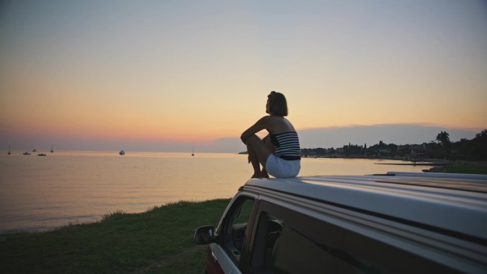 在周末度假期间，在面包车顶部观看宁静日落景色的女子的SLO MO镜头
