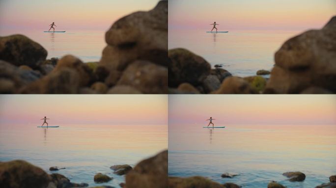 日落时分，女子在田园诗般的海上桨板上练习瑜伽的慢镜头
