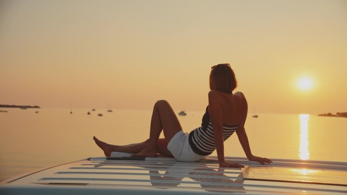 日落时分，女子在海边露营车上放松的慢镜头镜头