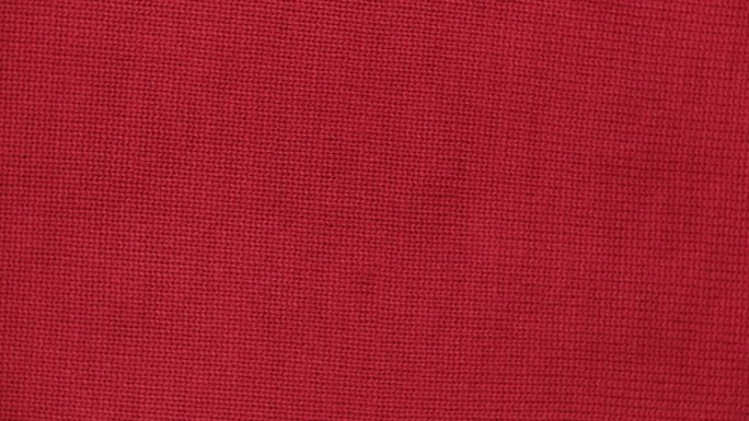 柔软的针织羊毛详细的纹理。天然织物近距离针织图案。红色针织品，暖羊绒表面。旋转,宏。舒适的纺织背景。