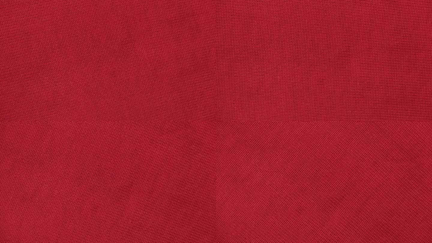 柔软的针织羊毛详细的纹理。天然织物近距离针织图案。红色针织品，暖羊绒表面。旋转,宏。舒适的纺织背景。
