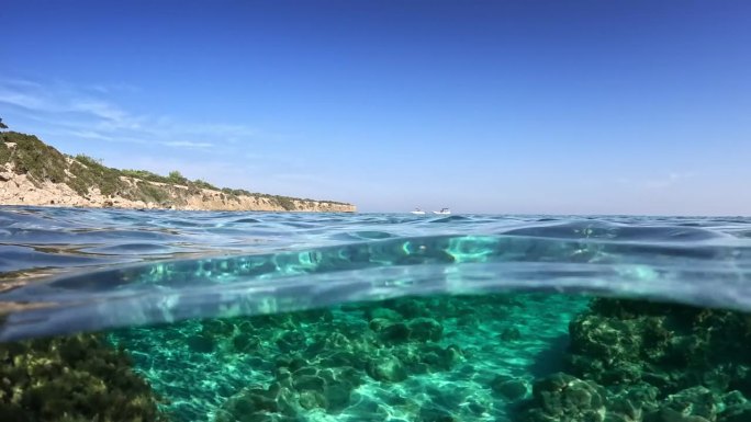 镜头慢慢移动到塞浦路斯海岸清澈的绿松石海水中。在塞浦路斯的蓝色泻湖海滩上，水晶般清澈的海水的分割慢动
