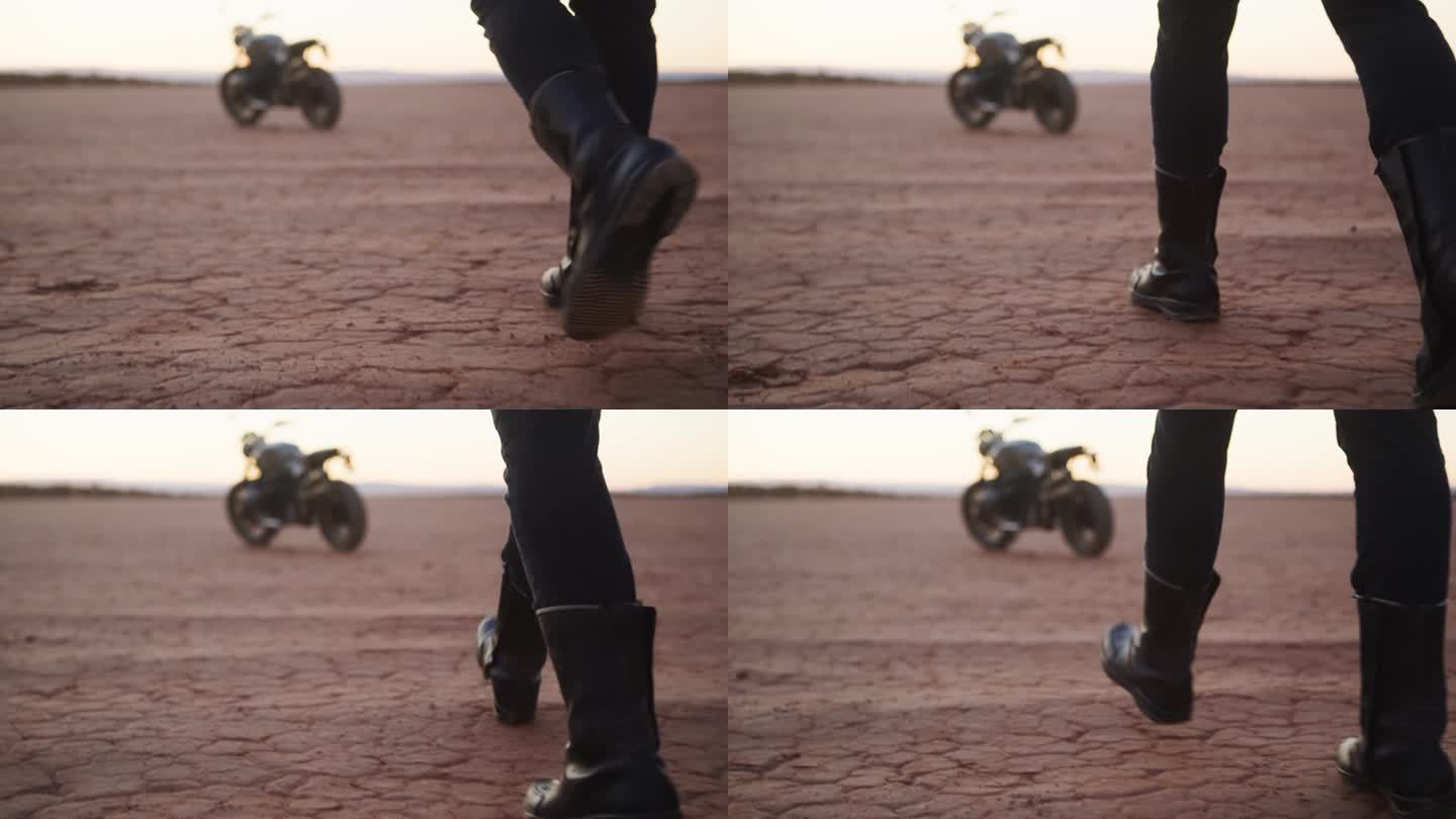 沙漠中一个人走向他的摩托车的靴子