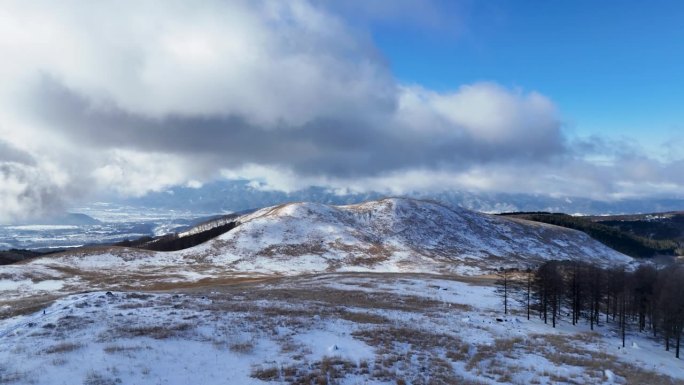 雪原高原鸟瞰图阳光明媚，但由于海拔高，云层很低，背景中可以看到城市