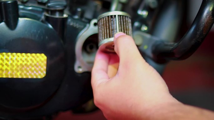 汽车修理工拆卸机油滤清器，拆卸摩托车上的机油滤清器进行保养或修理