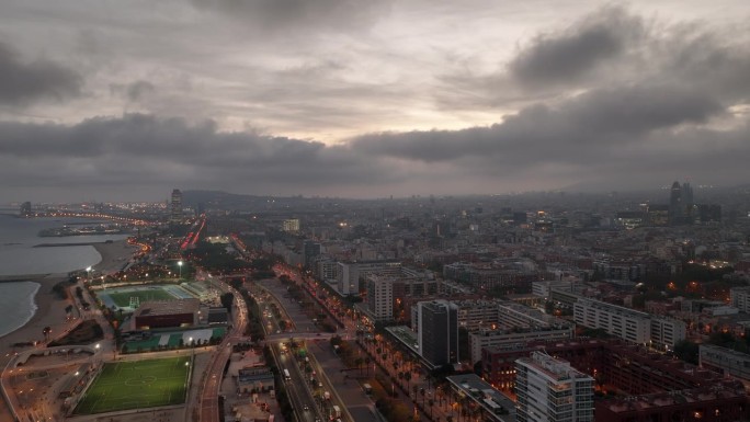 日落时间照明巴塞罗那城市景观海滩湾体育地面交通街道道路航拍全景4k西班牙