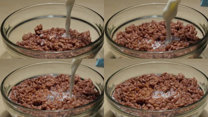 牛奶倒进巧克力麦片在一个透明的碗里，早餐特写镜头