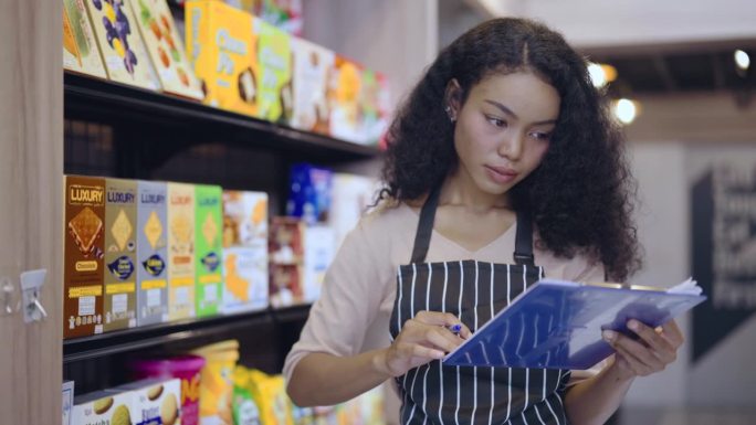 一名年轻女子在超市用条码扫描器清点货架上的商品。