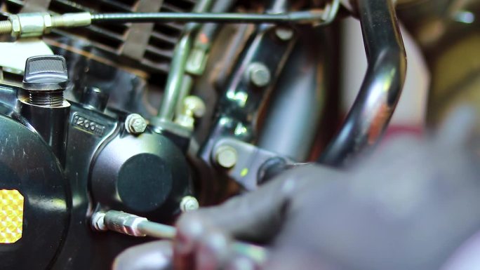 摩托车修理工拆下摩托车机油滤清器盖更换机油滤清器。拆下摩托车上的机油滤清器盖进行保养或修理