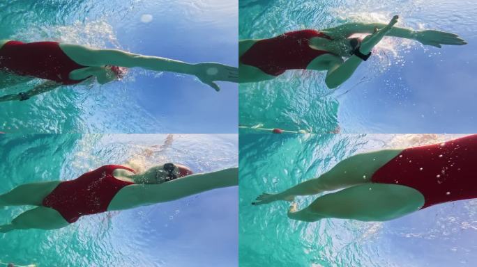 在阳光明媚的日子里，坚定的运动女子在泳池里练习爬泳的低角度水下镜头