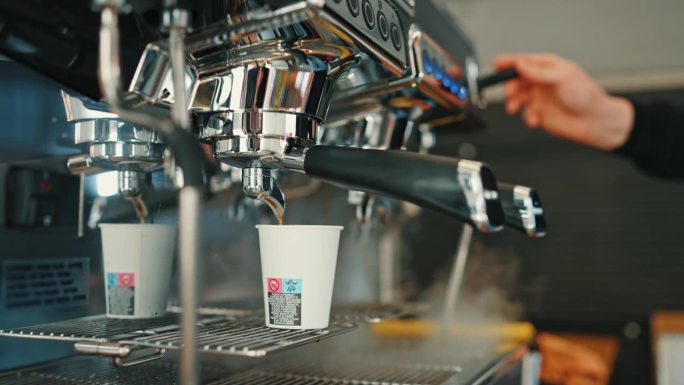 餐车里咖啡机的热气和咖啡师用倒进杯子的咖啡制作牛奶的特写