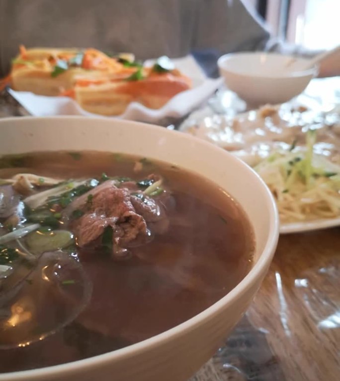餐厅桌子上的越南河粉汤、越南米和越南肉的特写垂直照片