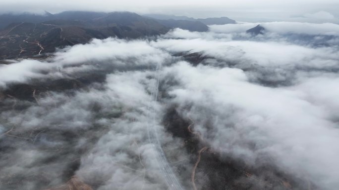 俯瞰春天云雾缭绕下贯穿山间田野的高速公路