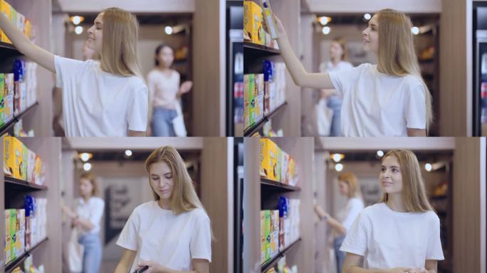 年轻漂亮的女消费者从货架上挑选产品。站在货架附近，在杂货店/超市购物。