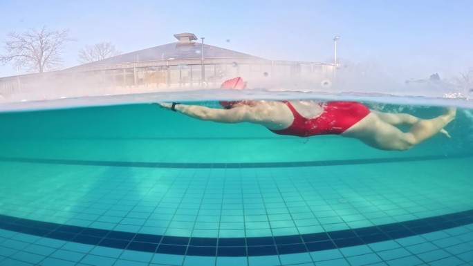 身穿红色潜水服的运动女子在旅游胜地游泳池游泳的部分水下锁定镜头