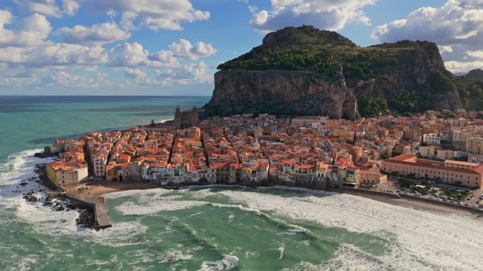 西西里岛中世纪村庄塞法鲁的航拍照片。在意大利西西里岛的切法卢，在山脚下的橙色屋顶的老城上空飞行