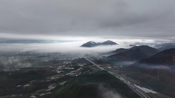 春天云雾缭绕下贯穿山间田野的高速公路