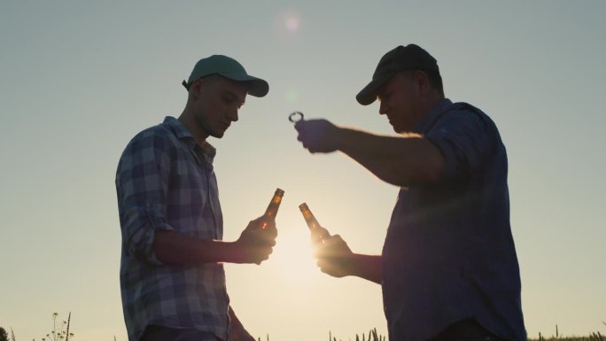 两个农民打开啤酒瓶，碰杯喝起来。