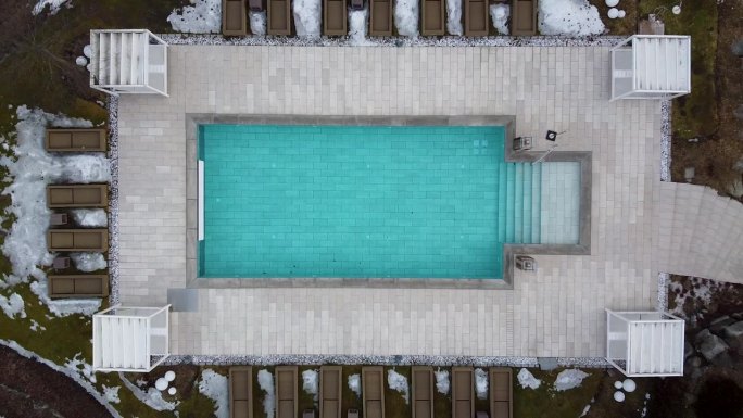 在阿尔卑斯山的一个豪华度假胜地，当无人机直接起飞时，游泳池的颜色会变得更蓝