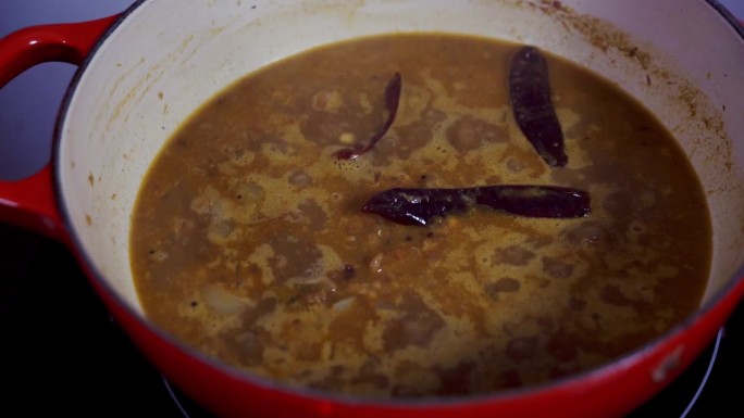 把咖喱放在锅里小火炖，里面放三个红辣椒来增加辣味