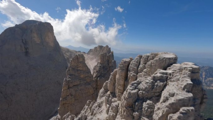 在夏季，自由式无人机在白云石山脉的高岩石山峰上飞行，背景是山谷。意大利。空中废票