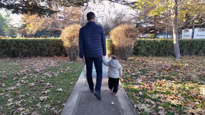秋天，父亲牵着蹒跚学步的孩子走在公园的小路上。满是秋叶。父子情谊。翻译过来就是:冰淇淋。
