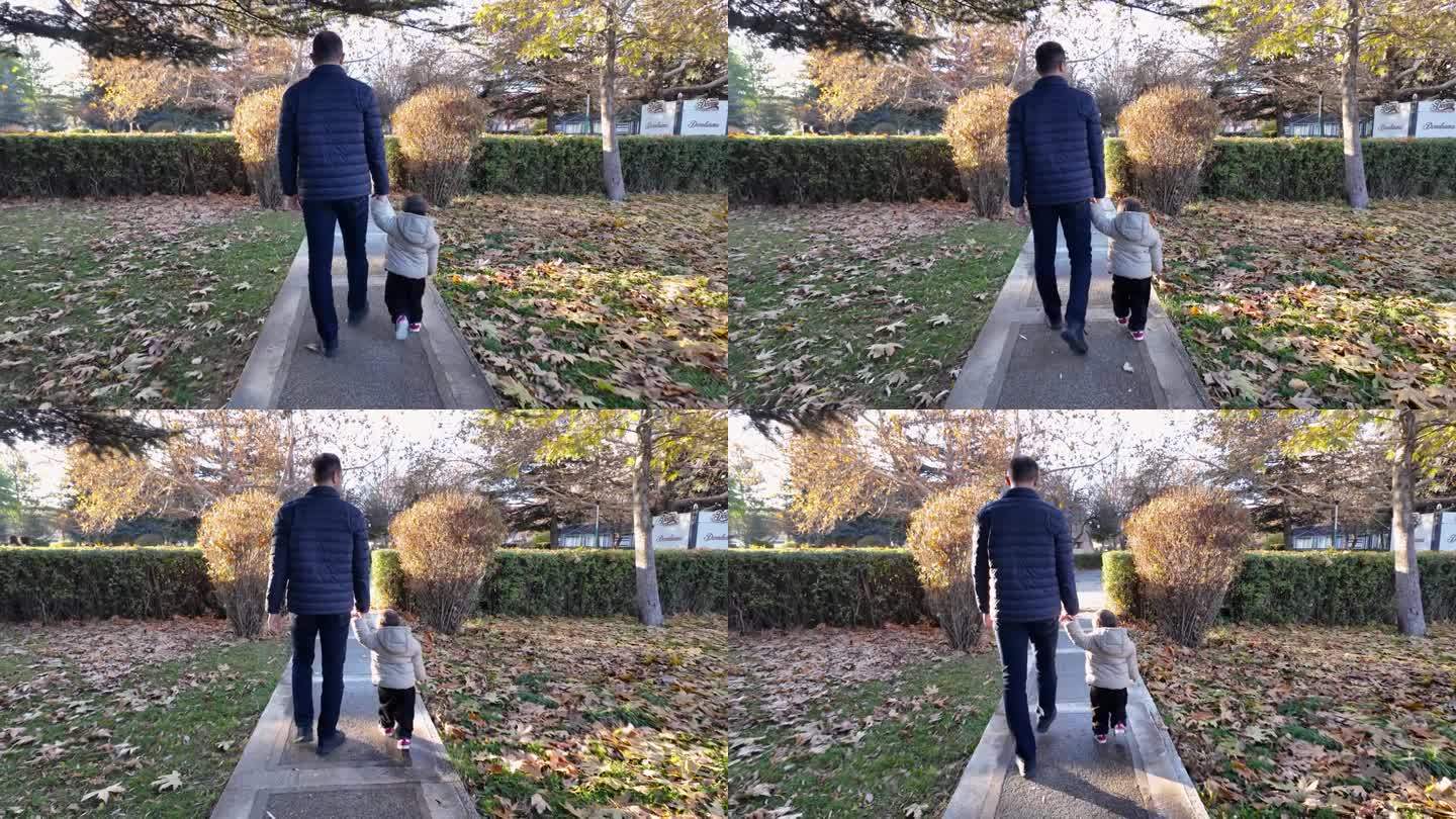 秋天，父亲牵着蹒跚学步的孩子走在公园的小路上。满是秋叶。父子情谊。翻译过来就是:冰淇淋。