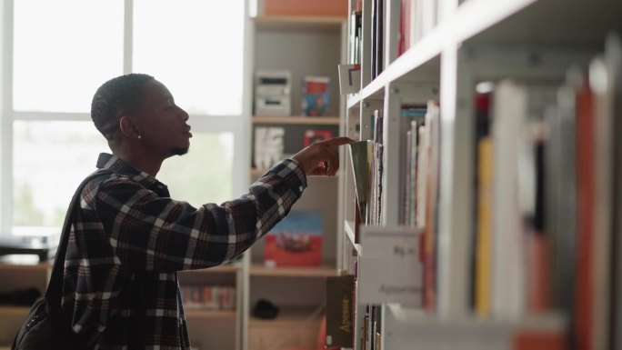 一个黑人在图书馆的书架上找书