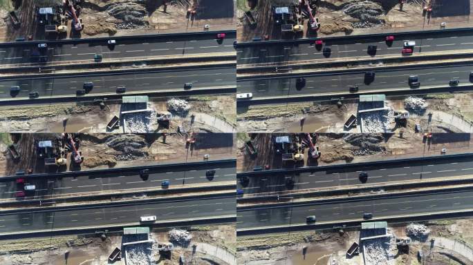 无人机从高速公路的建筑工地拍摄的。汽车从左向右和从右向左穿过马路。公路两旁有机械和碎石。