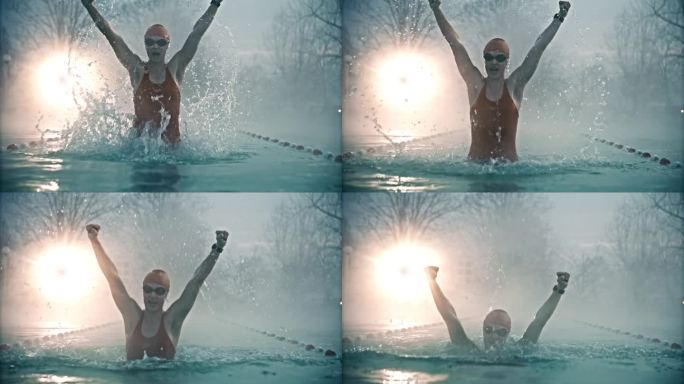 在雾蒙蒙的早晨，兴奋的女游泳运动员从游泳池中抬起双臂，尖叫着