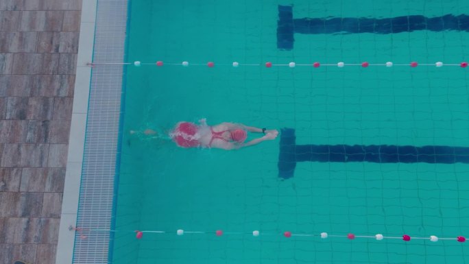 正上方的照片是一名穿着红色泳衣的女子在户外度假胜地的游泳池里游泳