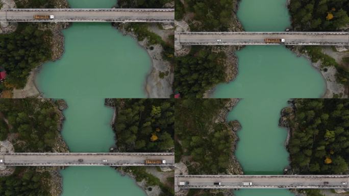 无人机直接捕捉到车辆在绿松石河上过桥的画面，河的两边都是树木