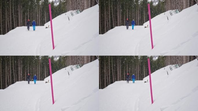 一对游客夫妇在冬季暴风雪中经过奥地利阿尔卑斯山的徒步旅行路线标记杆