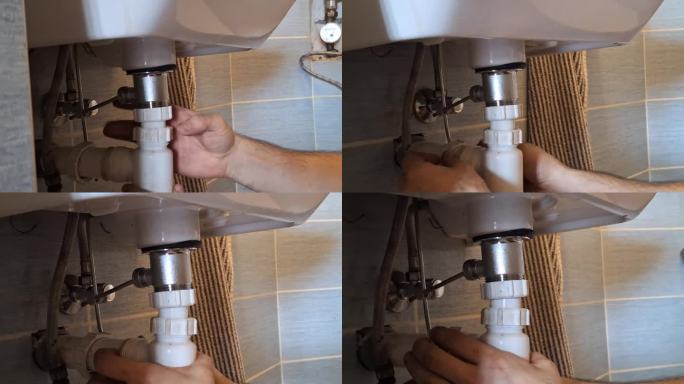 水管工在修理污水的隔臭器。一个男人的手在浴室的洗脸盆下面固定装置。家政、工艺和建筑的概念。
