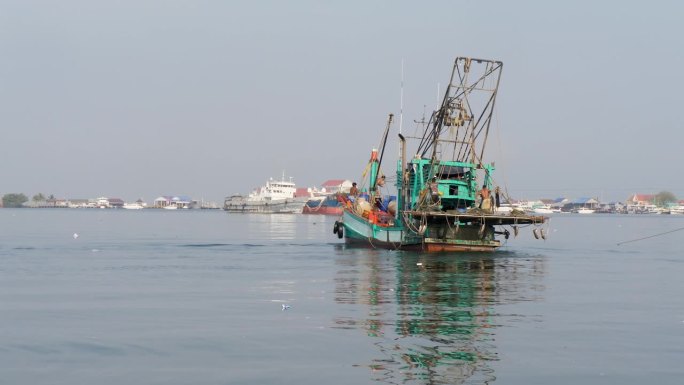 饱经风霜的木制捕蟹船驶离渔港