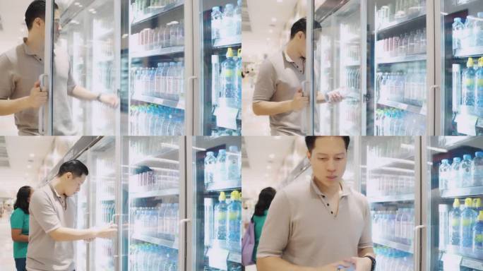 一名亚洲男子从超市的冷冻箱中取出瓶装水。
