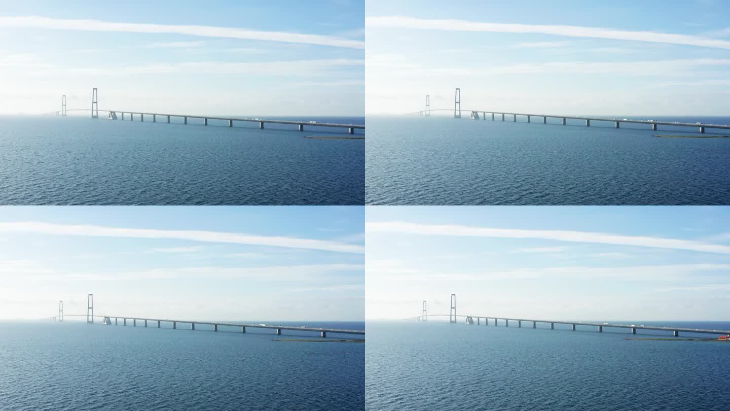 在平静的海面上，巨大的带式大桥上有移动的车辆