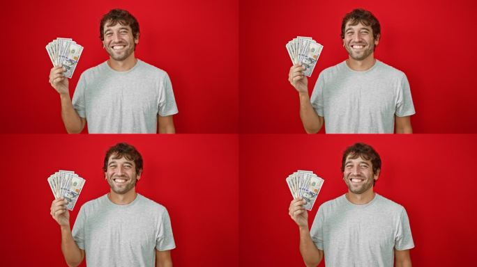 一个开朗的年轻人，充满自信，拿着美钞，带着充满喜悦的微笑，在孤立的红色背景上散发着积极的光芒。