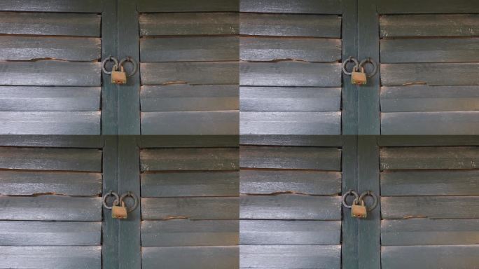 一把生锈的挂锁挂在一扇旧木窗上。