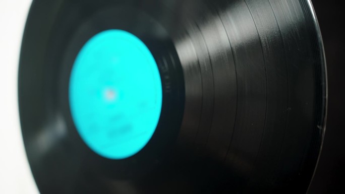 黑胶唱片，蓝色标签在黑白背景上旋转，选择性聚焦。