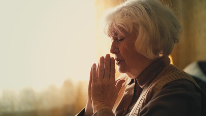 老年妇女在家祈祷，祈求上帝的帮助和治愈疾病