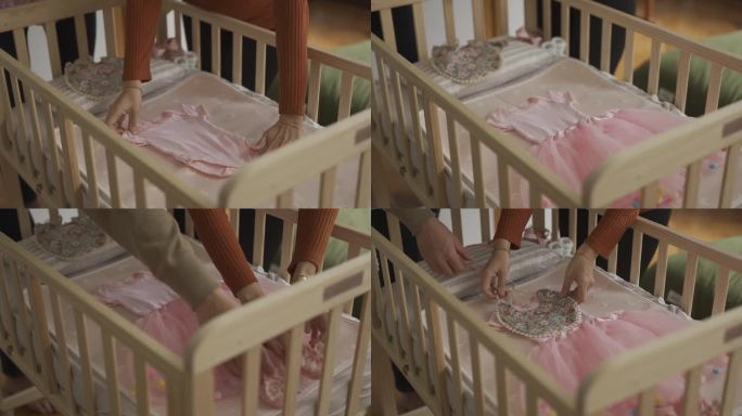 亚洲年轻夫妇装饰，把女婴的衣服放在卧室的婴儿床上