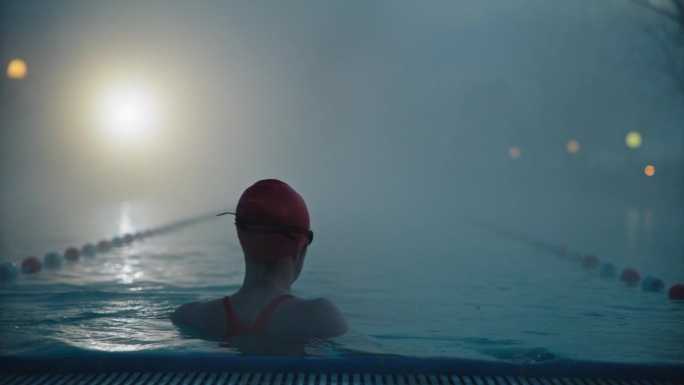 运动女子在黎明时分在旅游胜地的迷雾泳池游泳的慢动作镜头