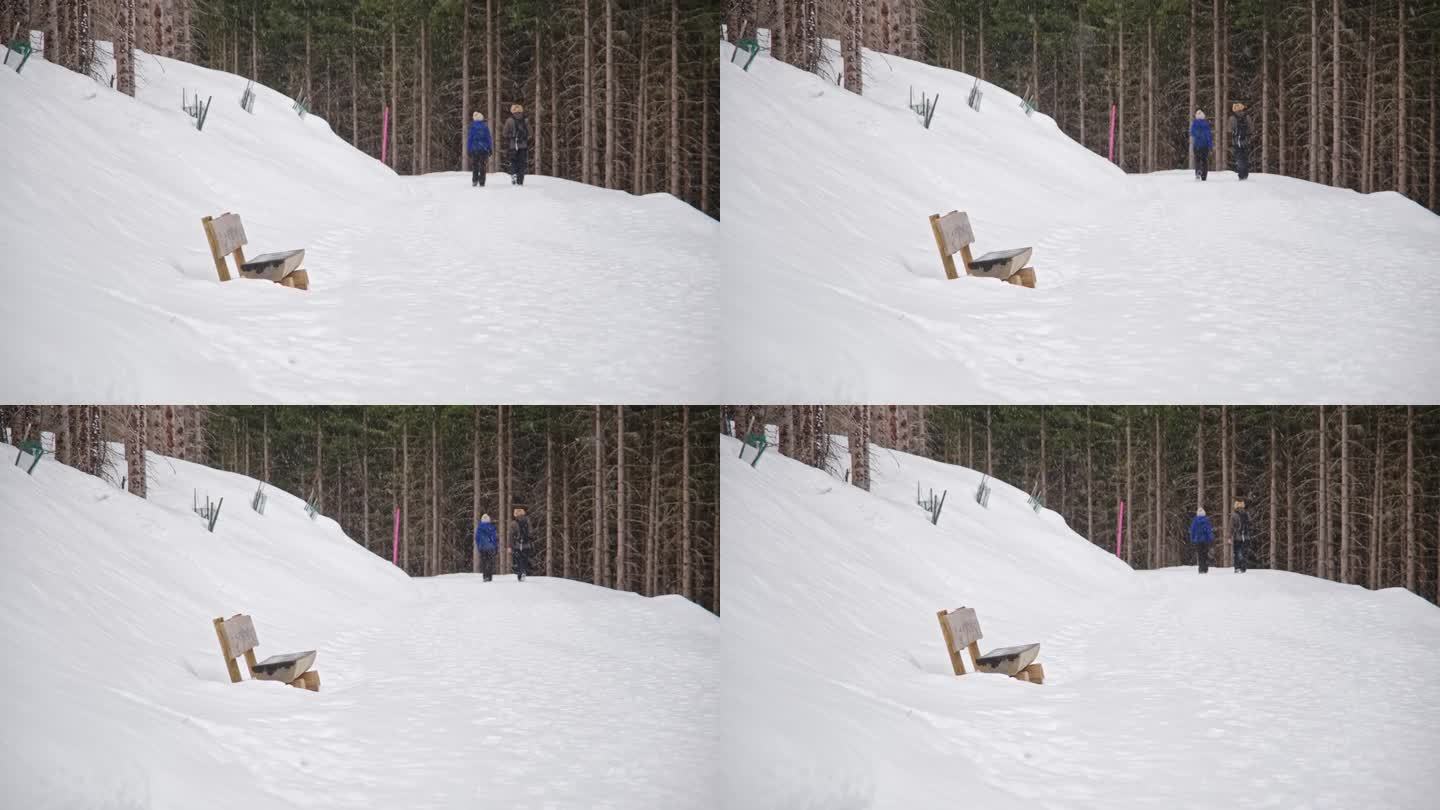 一对游客夫妇在冬季暴风雪中经过奥地利阿尔卑斯山的徒步旅行路线标记杆