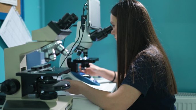 实验室工作人员在显微镜下分析血液样本。