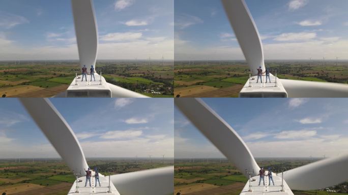 两名工程师站在风力发电机顶部检查风力发电机的状况。